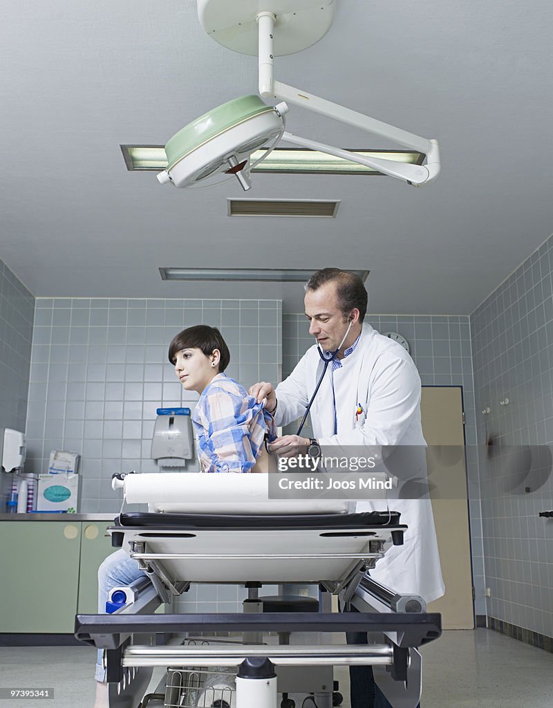 Doctor examing woman with stethoscope in hospital