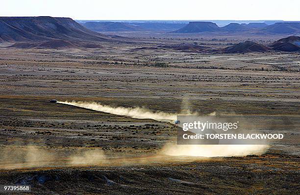 Four-wheel-drive vehicles leave a trail of bulldust as they traverse the ochre-hued formation known as The Breakaways near the opal mining town of...
