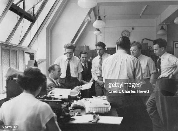 Staff in the Fetter Lane offices of the Daily Mirror newspaper, London, July 1953. Sports Editor J. Hutchinson sits centre, left. Original...