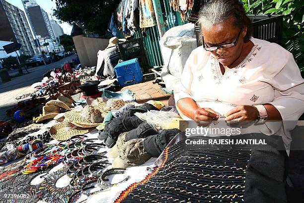 Street vendor Thenjiwe Zuma makes a traditional skirt at her business on the Durban beachfront on March 1, 2010. Durban, home to Africa's busiest...