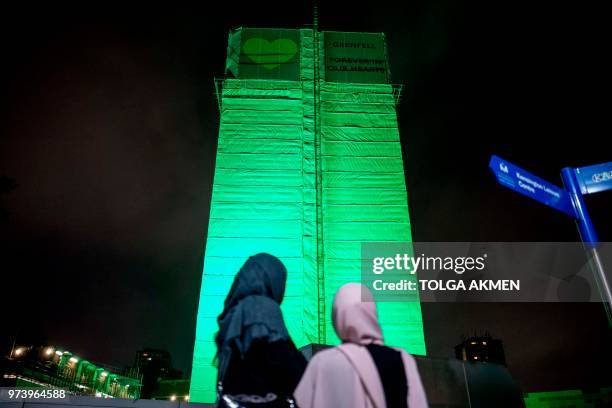 Members of the public hold a vigil and commemoration near Grenfell Tower in west London at midnight June 14, 2018 to honour the 71 people who died...