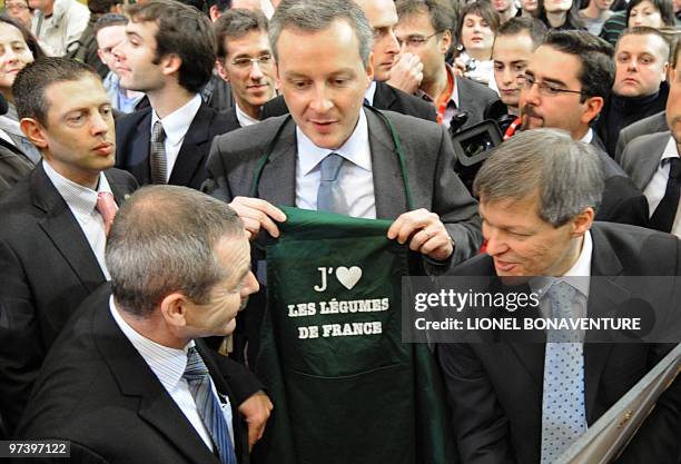 French Agriculture Minister Bruno Le Maire next to Europe's incoming farming commissioner, Romanian national Dacian Ciolos , holds a tee-shirt on...