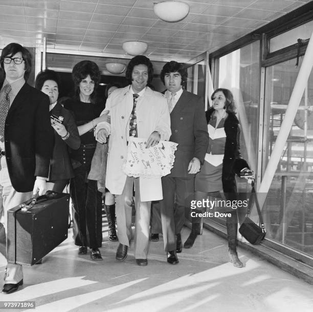 Welsh singer Tom Jones is escorted by two female fans at Heathrow airport in London as he prepares to fly to the United States for a tour on 7th...