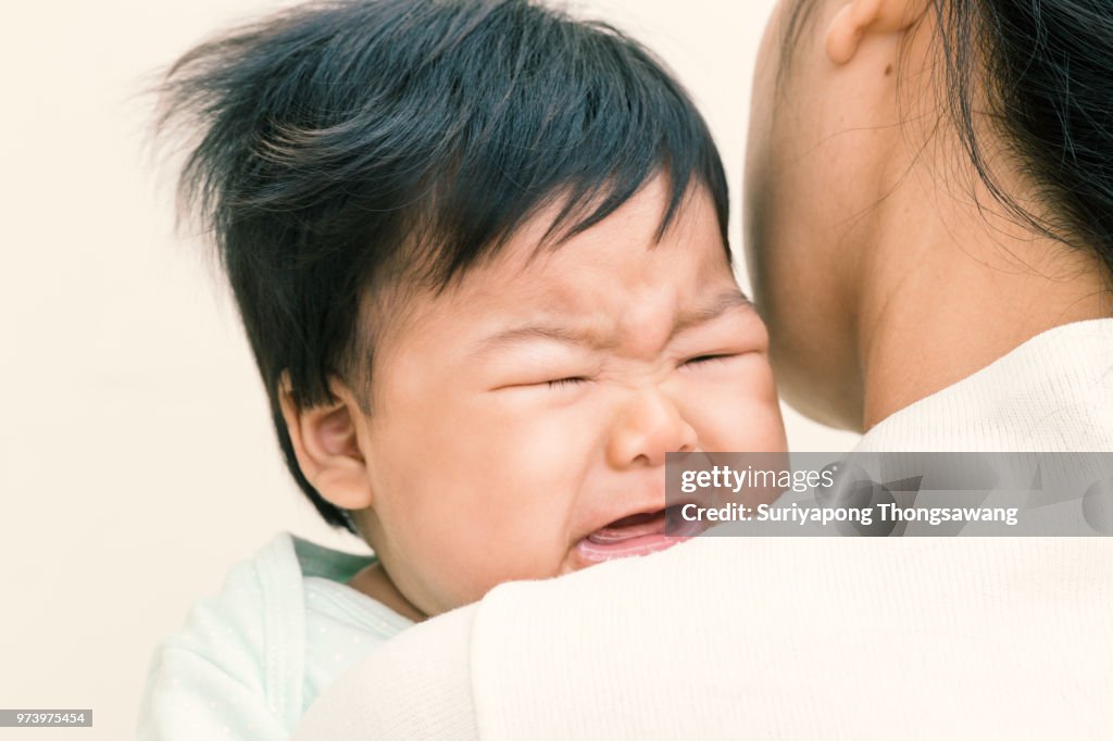 Entzückende asiatische Baby krank und auf Mama Schulter Weinen. (Vintage Ton)