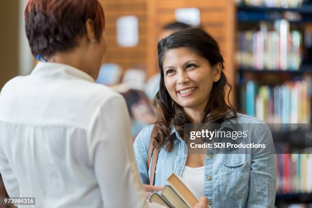 librarian helps female college student - librarian stock pictures, royalty-free photos & images