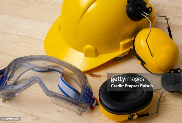 protective clothing, helmet, gloves and glasses. hearing protectors. safety accessories on a wooden table. black background. - abbigliamento da lavoro foto e immagini stock