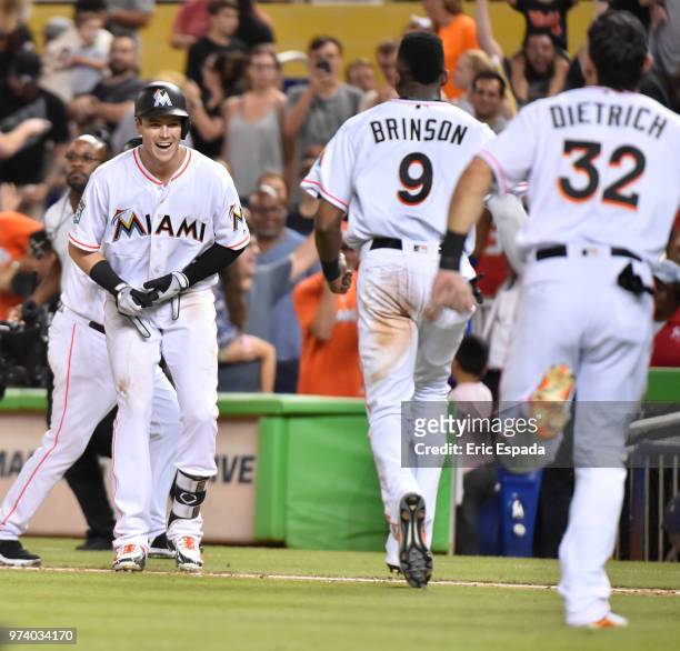 Lewis Brinson and Derek Dietrich of the Miami Marlins run towards Brian Anderson after he hit a sacrifice fly to win the game against the San...