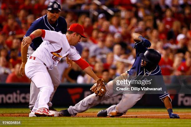 Manuel Margot of the San Diego Padres slides into third base against Jedd Gyorko of the St. Louis Cardinals for a triple in the sixth inning at Busch...