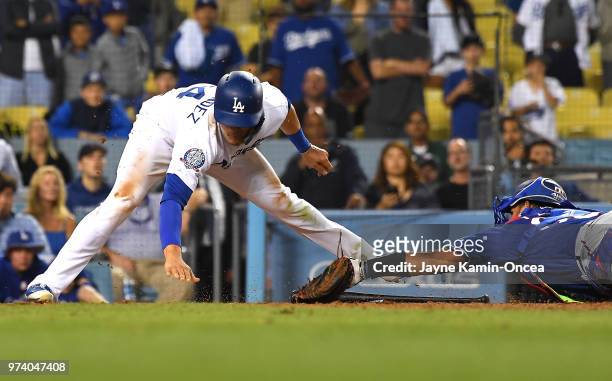Enrique Hernandez of the Los Angeles Dodgers beats the tag by Carlos Perez of the Texas Rangers in the eleventh inning at Dodger Stadium on June 13,...
