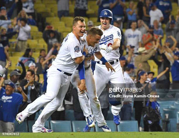 Joc Pederson and Ross Stripling celebrate with Enrique Hernandez of the Los Angeles Dodgers as they defeated the Texas Rangers in the eleventh inning...