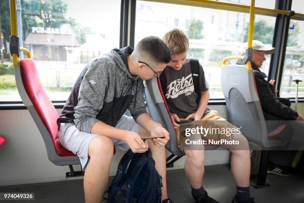 Two teenagers are seen using mobile devices in a public tram in Warsaw, Poland on June 12, 2018.