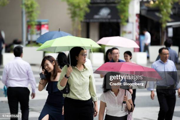 Pedestrians holding umbrella walk through the central business district of Singapore, on Wednesday, June 13, 2018. Tourism as well as the consumer...