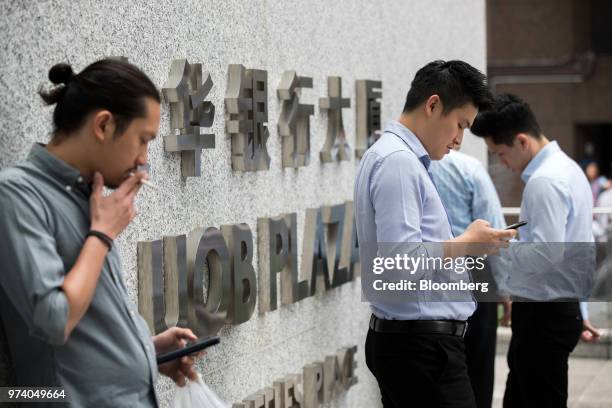 People use mobile phone outside the UOB Plaza in the central business district of Singapore, on Wednesday, June 13, 2018. Tourism as well as the...