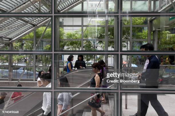 People ride an escalator and descend a flight of stairs to a MRT station in the central business district of Singapore, on Wednesday, June 13, 2018....