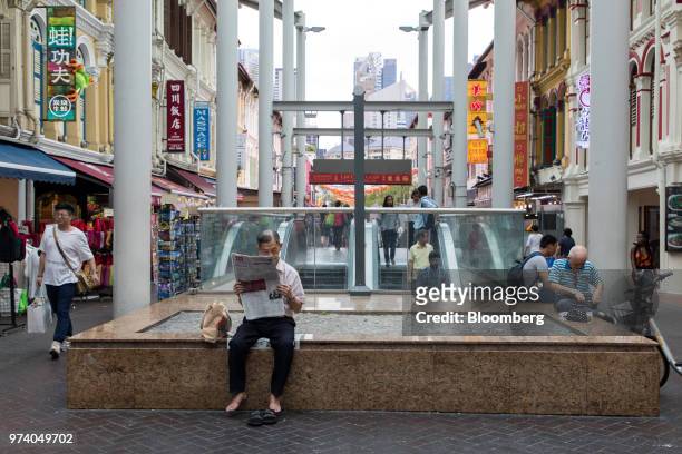 Man sits reading a newspaper nest to an escalator in the Chinatown area of Singapore, on Wednesday, June 13, 2018. Tourism as well as the consumer...