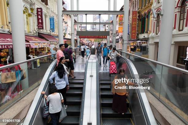 People ride an escalator in the Chinatown area of Singapore, on Wednesday, June 13, 2018. Tourism as well as the consumer sector will likely see a...