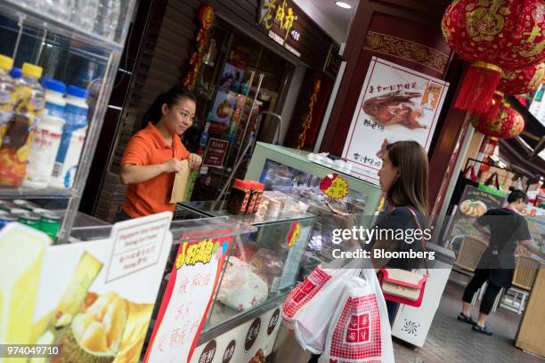 Vendor, left, talks to a customer at a stall in the Chinatown area of Singapore, on Wednesday, June 13, 2018. Tourism as well as the consumer sector...