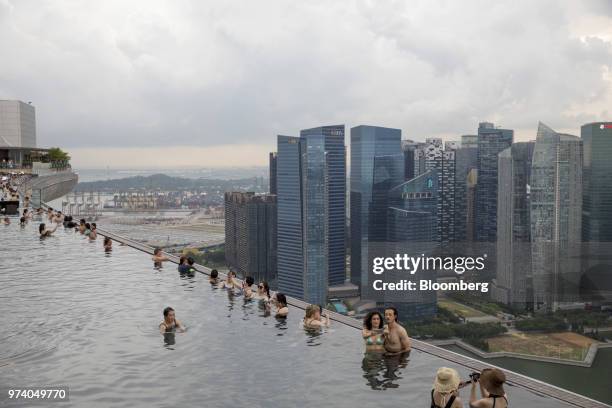 People take selfies in an infinity pool at the Marina Bay Sands hotel as commercial buildings stand in the central business district of Singapore, on...