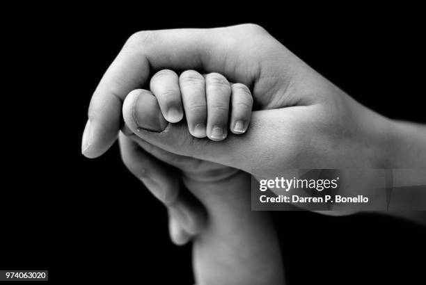 small and big hands clasped together - black and white hands stock pictures, royalty-free photos & images