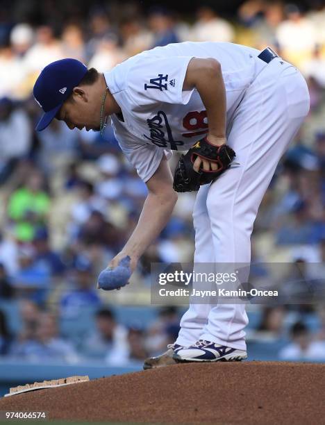 Kenta Maeda of the Los Angeles Dodgers uses a rosin bag to dry his hand before throwing the first pitch of the game against the Texas Rangers at...