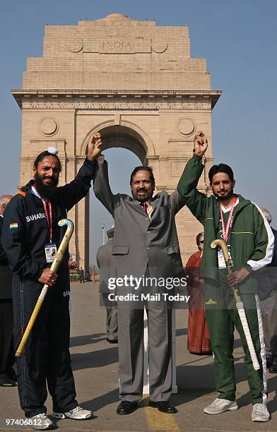 Suresh Kalmadi, president of Indian Olympic Association, holds hands of Indian hockey team captain Rajpal Singh, left, and Pakistan hockey team...