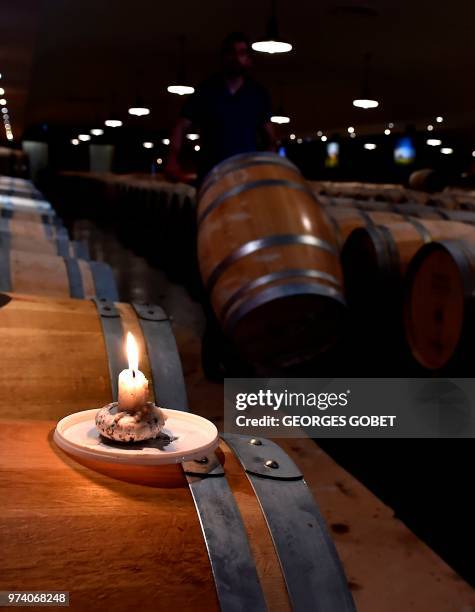 This photo taken on May 14, 2018 shows a burning candle on a Sauternes wine barrel used to light sulfur pastilles in the wine cellar of the Chateau...