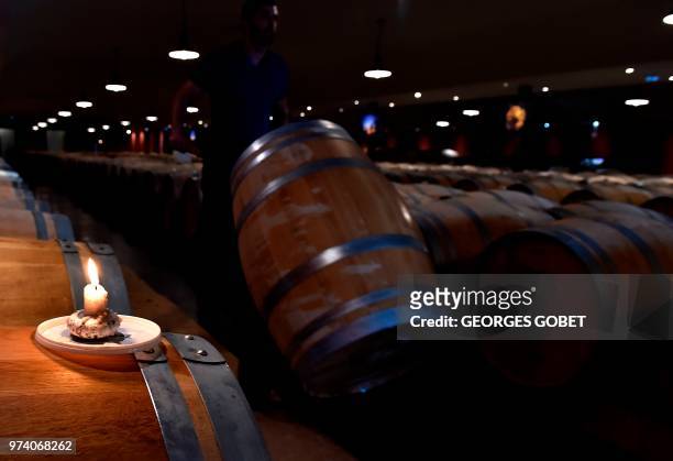 This photo taken on May 14, 2018 shows a burning candle on a Sauternes wine barrel used to light sulfur pastilles in the wine cellar of the Chateau...