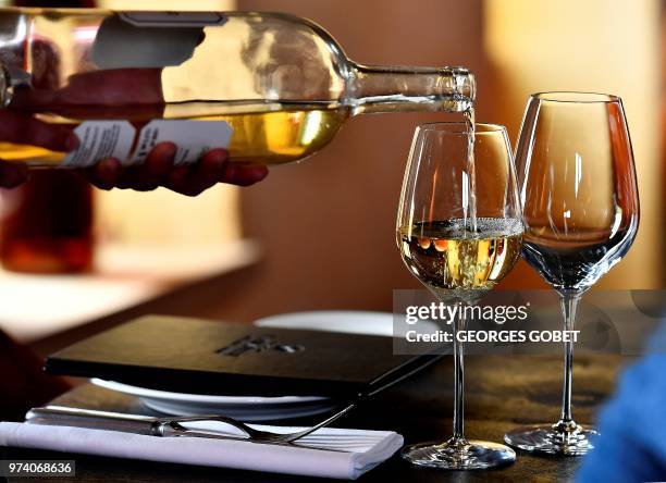 An person poors Sauternes wine on a glass on May 14, 2018 in Sauternes, western France. A sweet wine that is savoured with foie gras at Christmas: it...