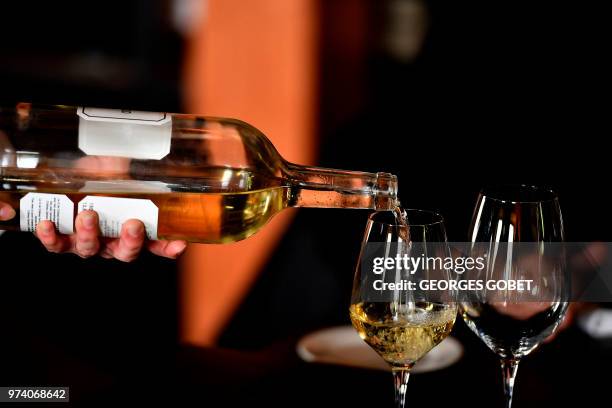 An person poors Sauternes wine on a glass on May 14, 2018 in Sauternes, western France. A sweet wine that is savoured with foie gras at Christmas: it...