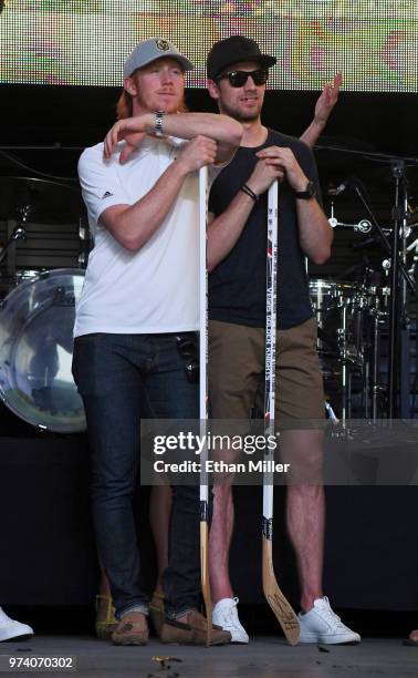 Cody Eakin and Shea Theodore of the Vegas Golden Knights rest on hockey sticks as they watch their teammates being introduced during the team's...