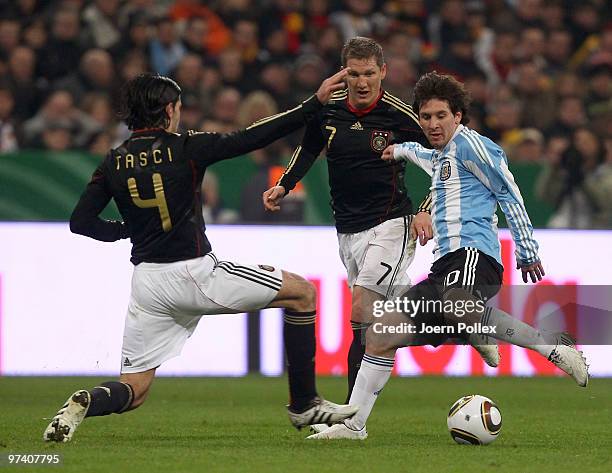 Bastian Schweinsteiger and Serdar Tasci of Germany and Lionel Messi of Argentina battle for the ball during the International Friendly match between...