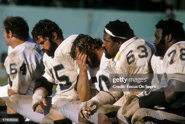 Offensive tackle John Vella, centre Dave Dalby with their heads down as teammates Art Shell, guard Gene Upshaw of the Oakland Raiders watches the...