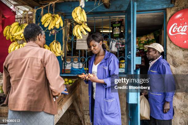 Silvia Gikuma, co-owner of a fresh-vegetable stall, sells fresh carrots to a costumer in Nairobi, Kenya, on June 11, 2018. Janeffer Wacheke and...