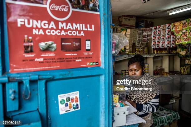 Janeffer Wacheke, co-owner of a fresh-vegetable stall, checks her account notebook while working at her stall in Nairobi, Kenya, on June 11, 2018....