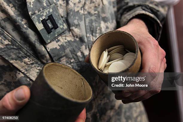 Army Chaplain Carl Subler opens a smoke grenade container he uses to carry communion wafers before conducting a Catholic Mass on March 3, 2010 at...