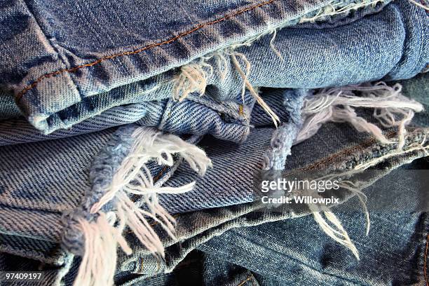 ragged old blue jeans in a messy pile - beaten up stockfoto's en -beelden