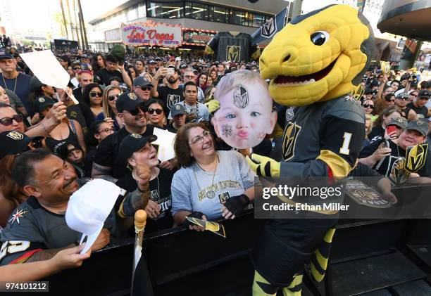 Vegas Golden Knights fan Miguel Sierra of Nevada watches as the Vegas Golden Knights mascot Chance the Golden Gila Monster signs his Halloween baby...