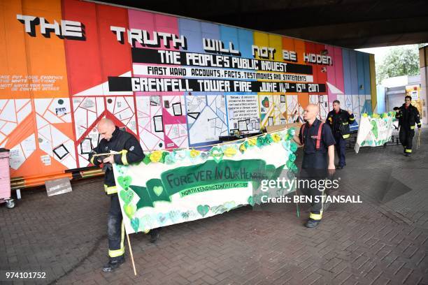 Firemen carry a banner by a memorial wall near Grenfell Tower on the anniversary of the Grenfell fire in west London on June 14, 2018. -...