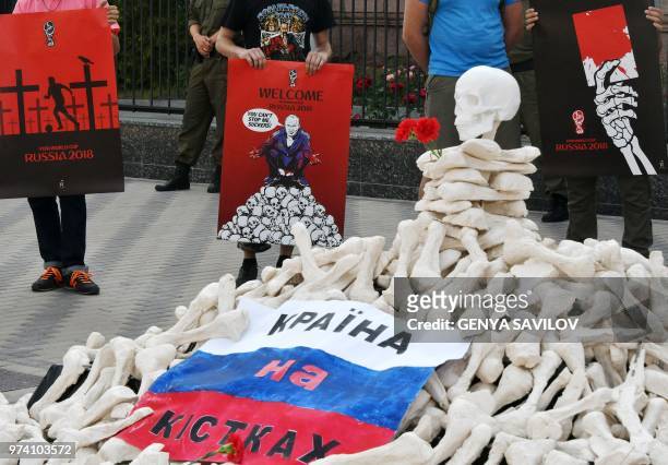 People hold placards with an appeal to boycott the Russia World Cup 2018 football tournament in front of the Russian Embassy in Kiev on June 14...