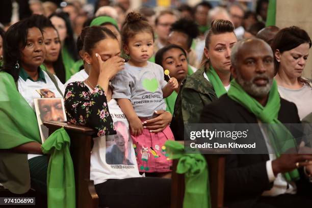 Woman holding a young girl looks emotional as she covers her face during the memorial service at St Helen's Church to mark the one year anniversary...