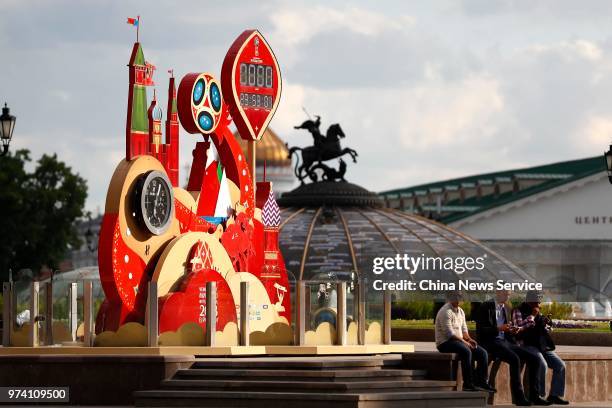 People sit in front of the Russia FIFA World Cup 2018 count clock near Red Square showing the minutes left until kick off of the first game on June...