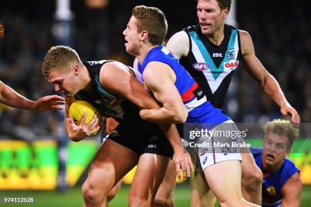 Dan Houston of Port Adelaide tackled by Lachie Hunter of the Bulldogs during the round 13 AFL match between Port Adelaide Power and the Western...