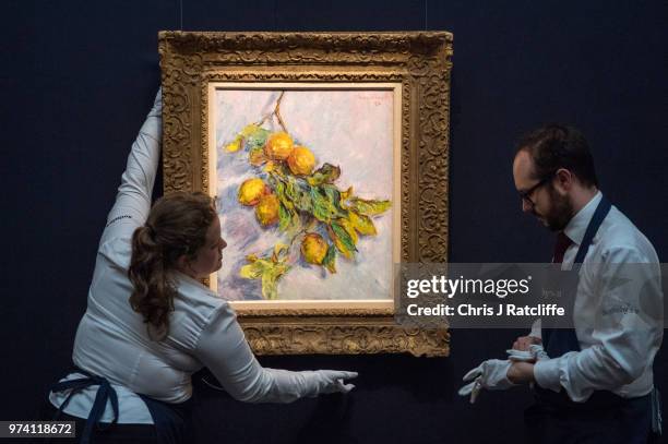 Two art handlers hang 'Citrons sur une branche' by Claude Monet during a preview of the Impressionist and Modern sale at Sotheby's on June 14, 2018...