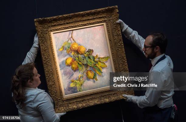 Two art handlers hang 'Citrons sur une branche' by Claude Monet during a preview of the Impressionist and Modern sale at Sotheby's on June 14, 2018...