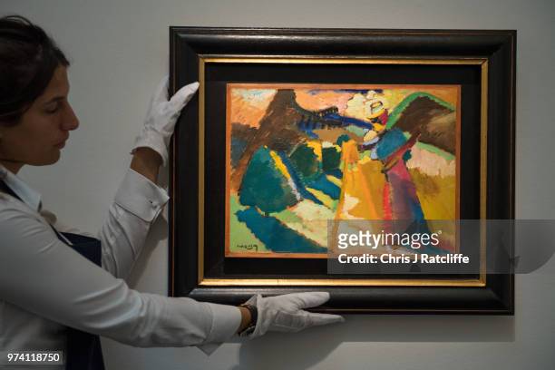 An art handlers 'Gabriele Munter im Freien vor der Staffelei' by Wassily Kandinsky during a preview of the Impressionist and Modern sale at Sotheby's...