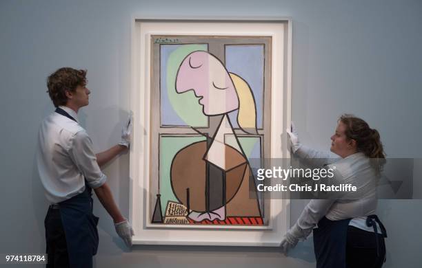 Art handlers hang 'Buste de femme de profil' by Pablo Picasso during a preview of the Impressionist and Modern sale at Sotheby's on June 14, 2018 in...