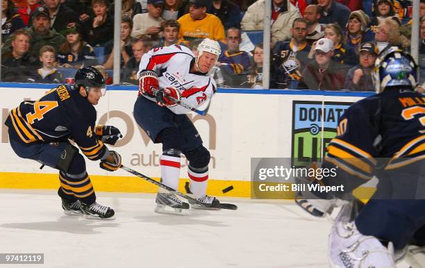 Jason Chimera of the Washington Capitals shoots the pucks against Andrej Sekera and Ryan Miller of the Buffalo Sabres on March 3, 2010 at HSBC Arena...