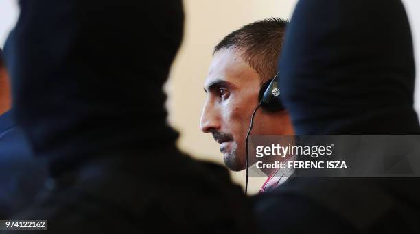 The main defendant Samsoor Lahoo stands among policemen during his trial on June 14, 2018 in Kecskemet, Hungary, where the court sentenced the four...