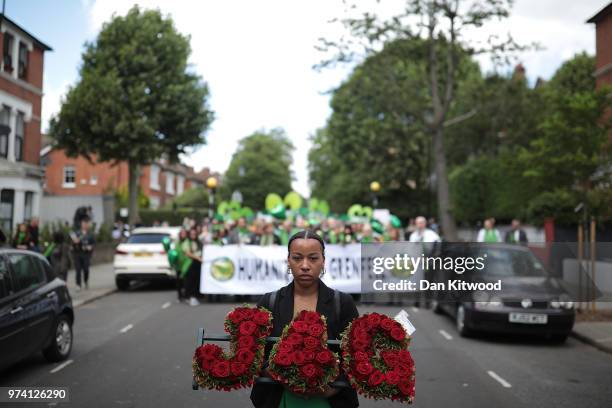Woman holds a floral tribute of red roses spelling 'J4G' as she walks to Wall of Truth to mark the one year anniversary of the Grenfell Tower fire on...
