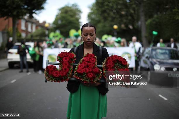 Woman holds a floral tribute of red roses spelling 'J4G' as she walks to Wall of Truth to mark the one year anniversary of the Grenfell Tower fire on...